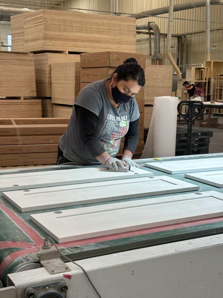 A worker hand finishing cabinet doors on the production floor
